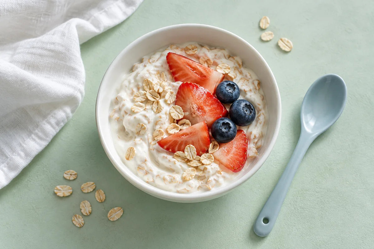 A berry yogurt bowl with oats and fresh fruit on a pale mint table